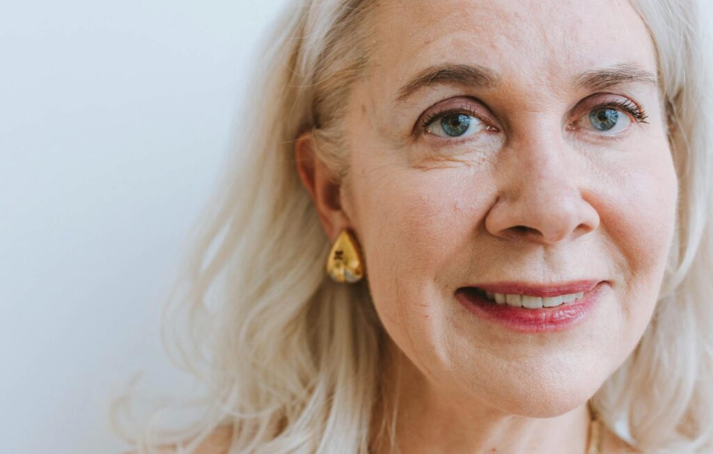 A smiling senior woman with earrings and necklace from a portrait session.